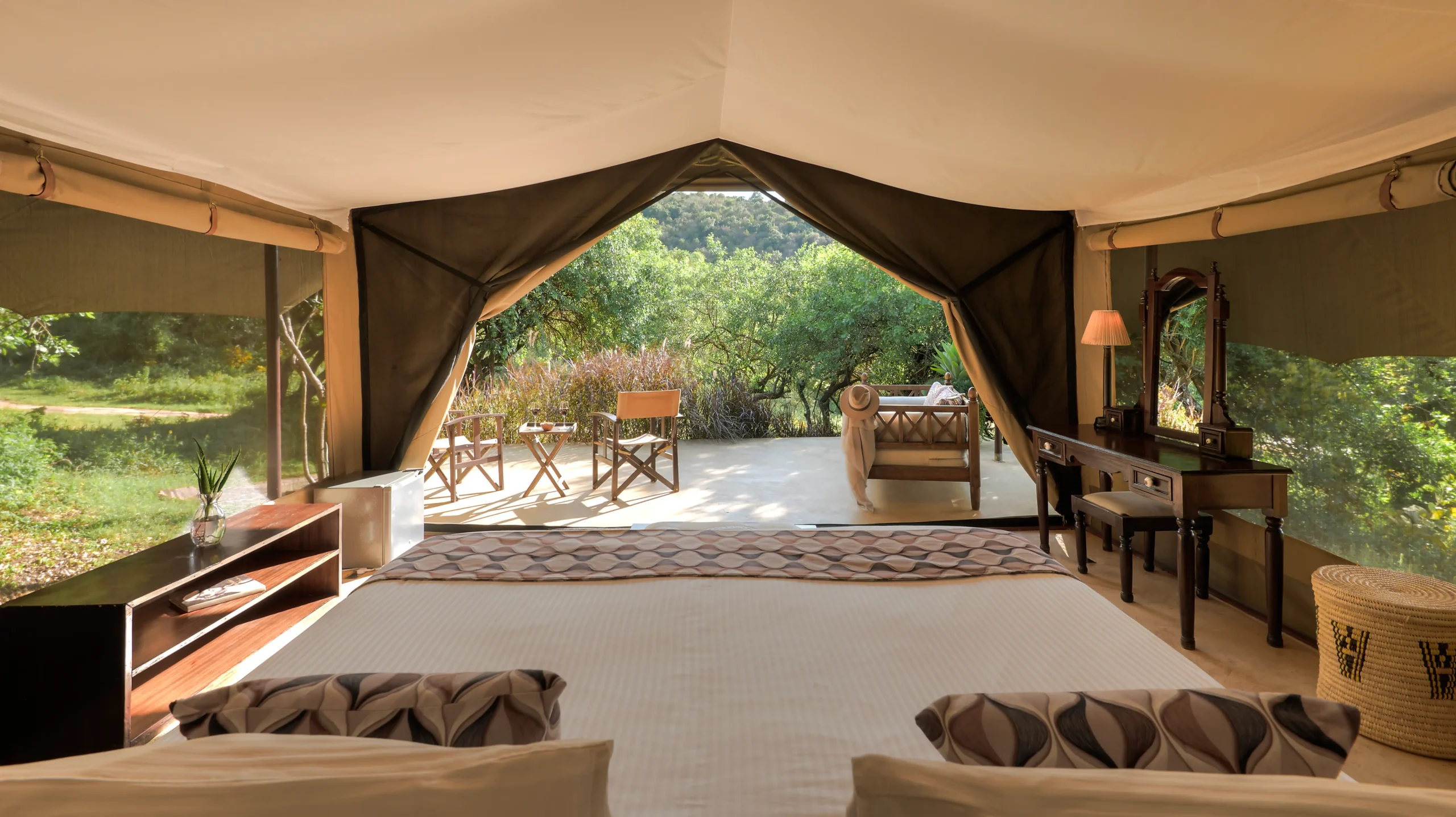 Tent interior with open canvas sides revealing the bush, Entumoto Safari Camp, Maasai Mara. Photo: Vanessa Knight