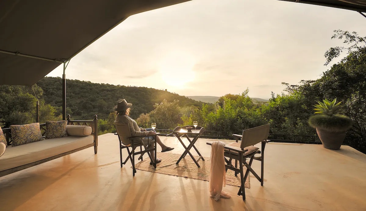 Guest with wine on a private veranda at sunset, Entumoto Safari Camp, Maasai Mara. Photo: Vanessa Knight