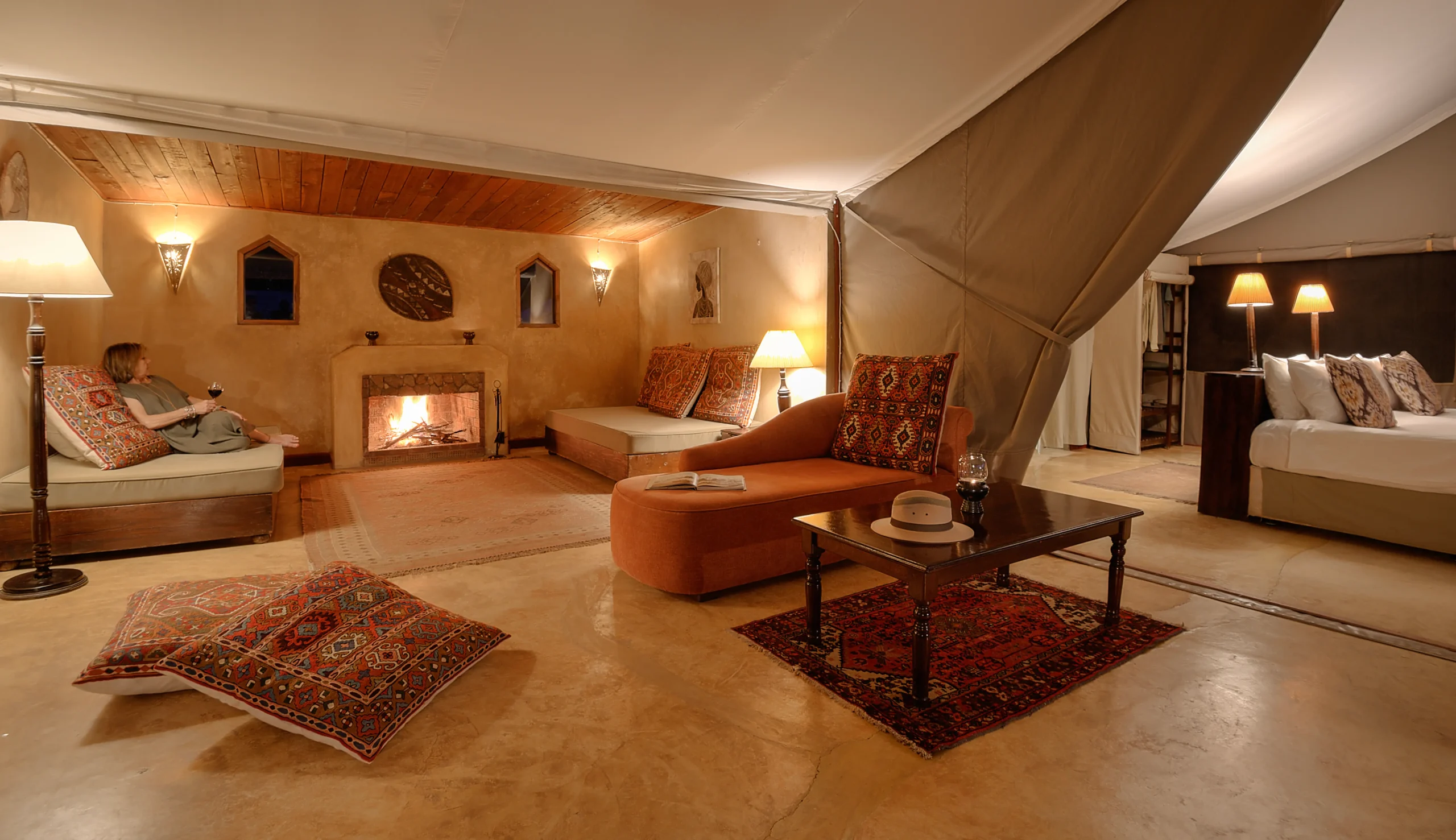 Main lodge living area with stone fireplace and kilim rugs, Entumoto Safari Camp. Photo: Vanessa Knight