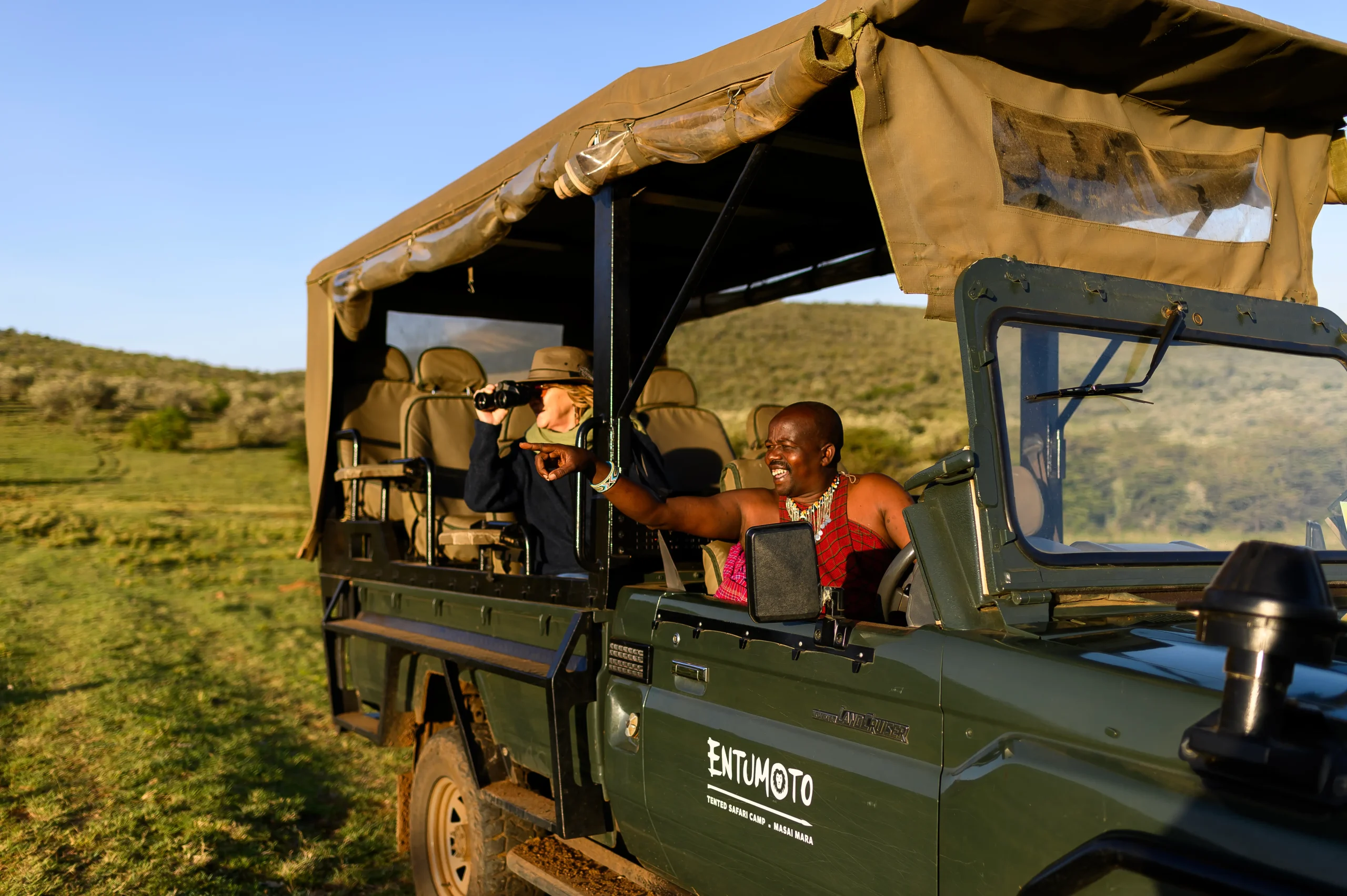 Maasai guide pointing out wildlife on a game drive, Entumoto Safari Camp, Maasai Mara. Photo: Vanessa Knight