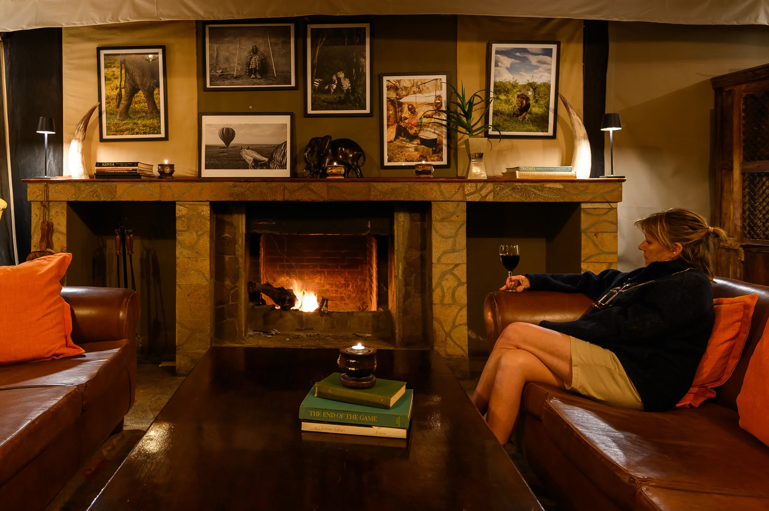 Guest with wine by the main lodge fireplace, Entumoto Safari Camp, Maasai Mara. Photo: Vanessa Knight